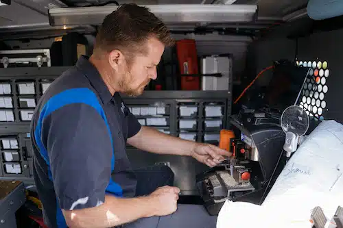 Noble locksmith cutting a new car key inside his van