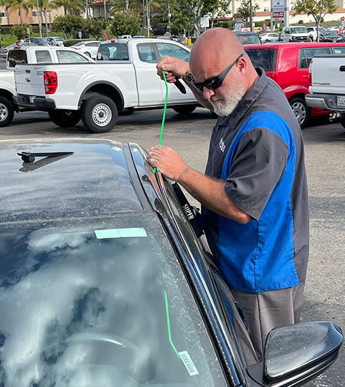 Locksmith using long reach tool to unlock a car